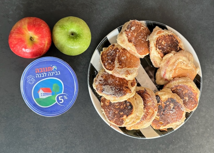 פנקייק גבינה ותפוחים, לצד גבינה לבנה ותפוחים ירוקים ואדומים.