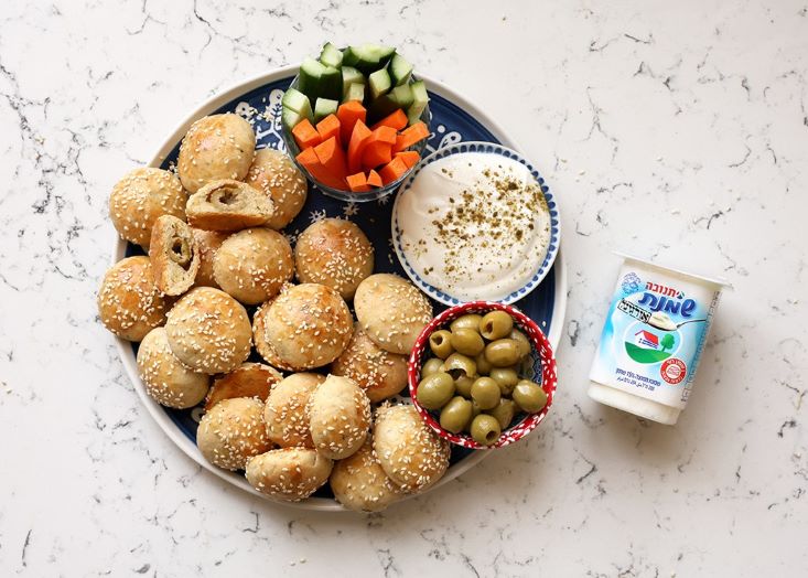 מיני לחמניות במילוי זיתים לצד שמנת חמוצה, זיתים וירקות.