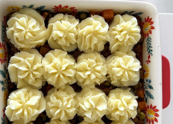 מזלפים פרחי פירה מעל הבולונז שיצא מהתנור.