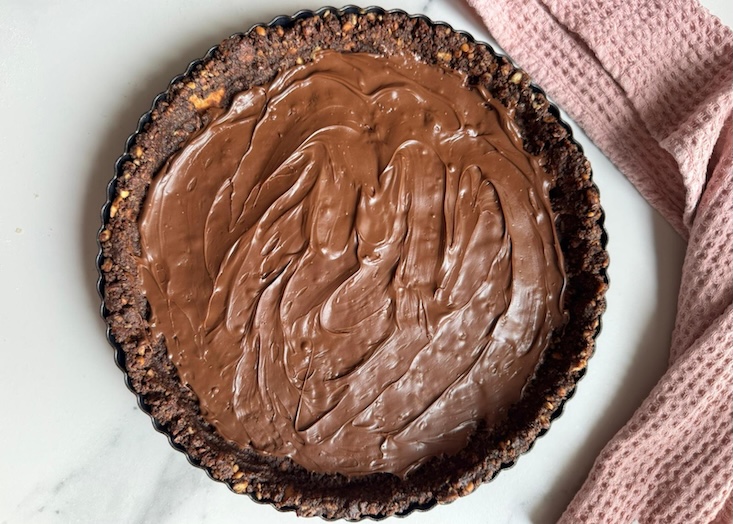 שלב שני - תהליך הכנה: בתבנית טארט משטחים את התערובת ומוסיפים ממרח נוטלה.