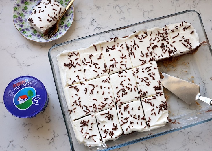 עוגת שוקולד, גבינה לבנה וקצפת, בקישוט סוכריות חומות.