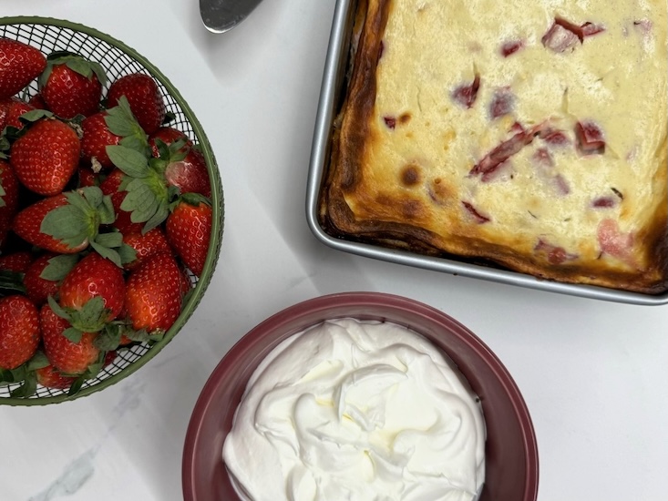 מוציאים את העוגה מהתנור, מקציפים את השמנת המתוקה עם יתר החומרים ומעל מקשטים בתותים.