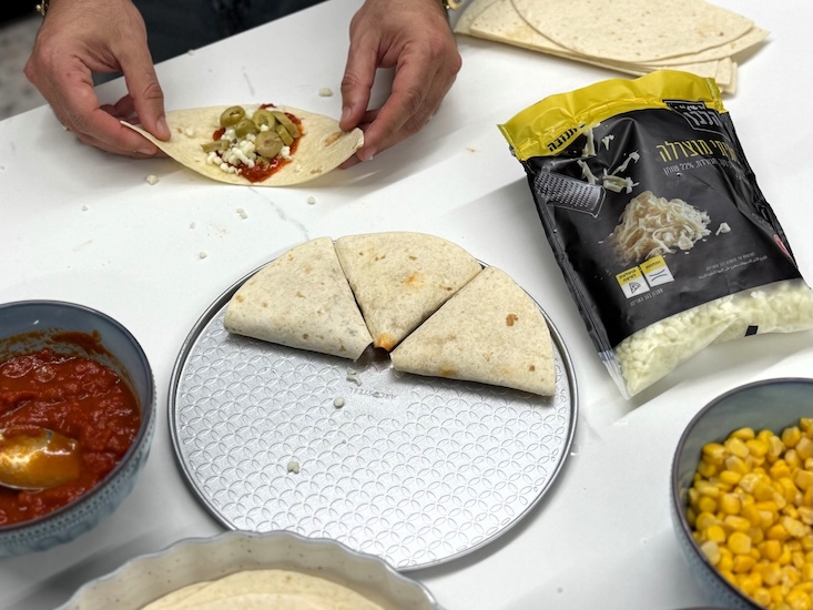 לאחר מריחת רוטב פיצה ובחירת תופסת, מקפלים את הטורטייה לצורת קונוס.