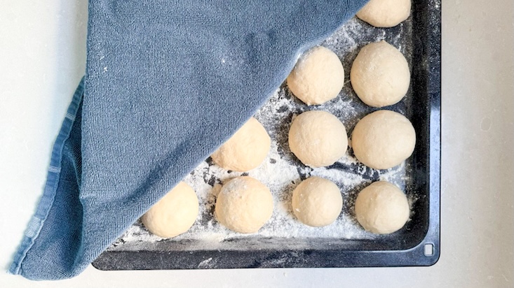מכדררים את הבצק ואת הכדורים מניחים למנוחה במגשים מרופדים קמח ומכסים.