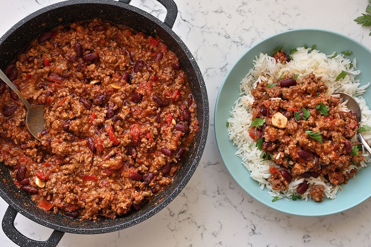 צ׳ילי קון קרנה בסיר, לצד צלחת אורז.
