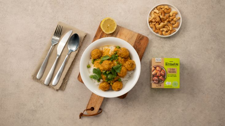 קערת קציצות טופו בקארי צהוב על אורז, מוגש לצד לימון פרוס, בוטנים וטופו.