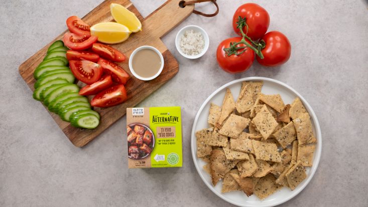 טופו קריספי אפוי מוגש לצד ירקות חתוכים וחבילת טופו רך.