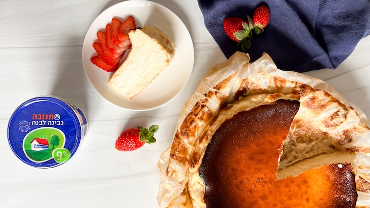 עוגת גבינה באסקית עם גבינה לבנה, מוגשת עם פרוסות תותים.