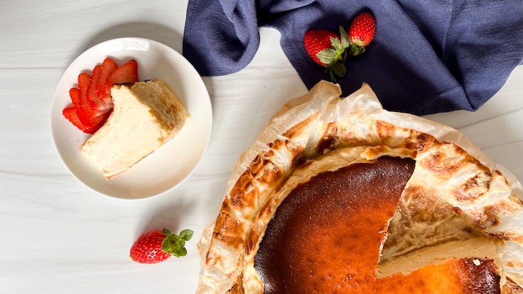 עוגת גבינה באסקית מוגשת עם תותים פרוסים.