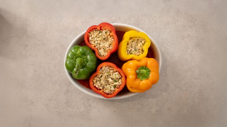 מסדרים את הפלפלים הממולאים בתבנית ומוסיפים רוטב עגבניות.