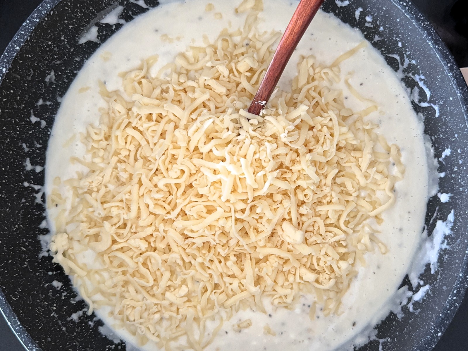 מוסיפים תבלינים וגבינה צהובה מגוררת ומערבבים עד שהרוטב מסמיך