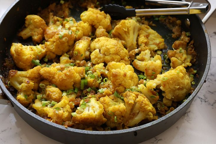 מפזרים בצל ירוק על הכרובית המוכנה בסיר.