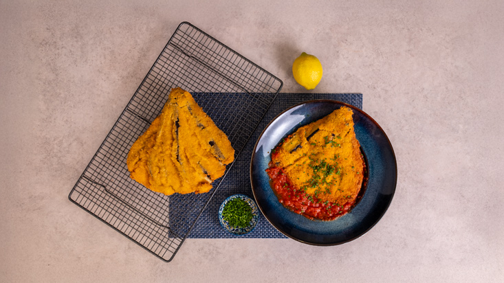 רוטב עגבניות על צלחת הגשה, חציל אפוי ומעל בזיליקום קצוץ.