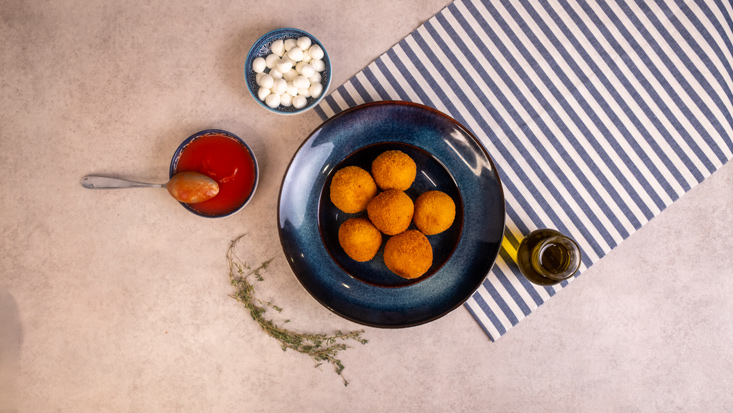 כדורי ארנציני פתיתים במילוי בייבי מוצרלה, לצד רוטב עגבניות ובייבי מוצרלה.