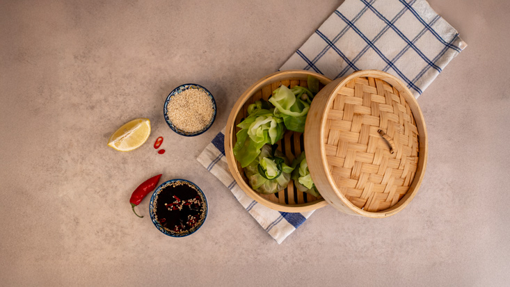 מגישים את הדים סאם כרוב במילוי בייבי מוצרלה בסיר אידוי, לצד פלח לימון, רוטב ותבלינים.