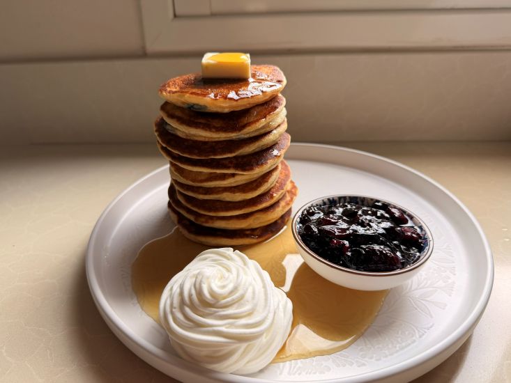 נגיש את ערימת הפנקייקים עם קצפת בצד, סירופ מייפל וקולי פירות יער.