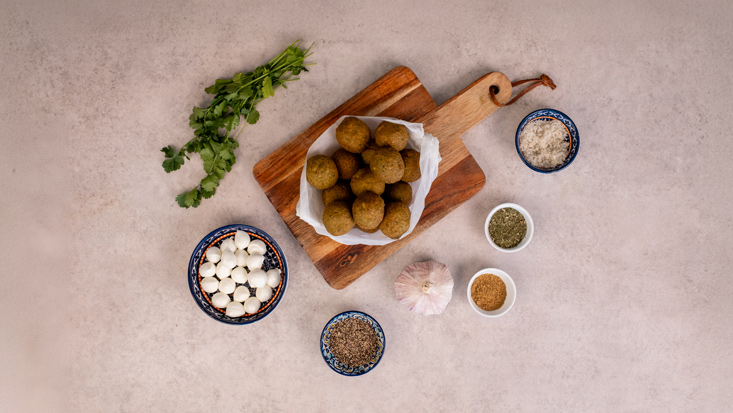 כדורי פלאפל עם בייבי מוצרלה, על נייר סופג, לצד בייבי מוצרלה, שום ותבלינים.