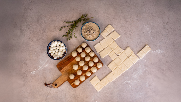 מניחים במרכז כל ריבוע בייבי מוצרלה של פיראוס וסוגרים לכדור.