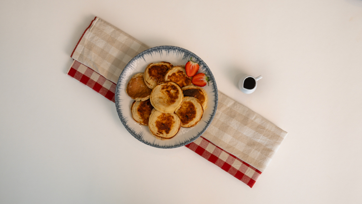 פנקייק יוגורט מוגש בצלחת לצד מייפל ותותים.