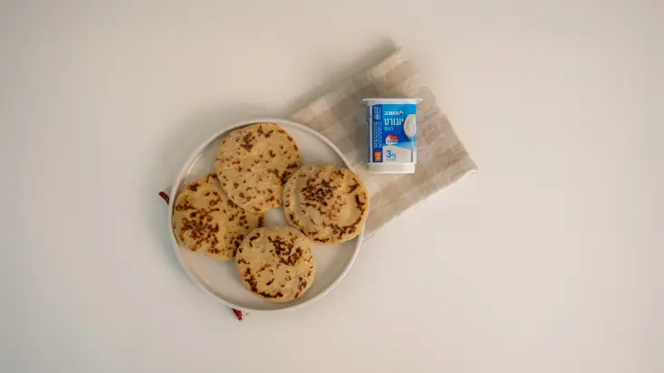 פיתות יוגורט בצלחת, לצד גביע יוגורט תנובה.