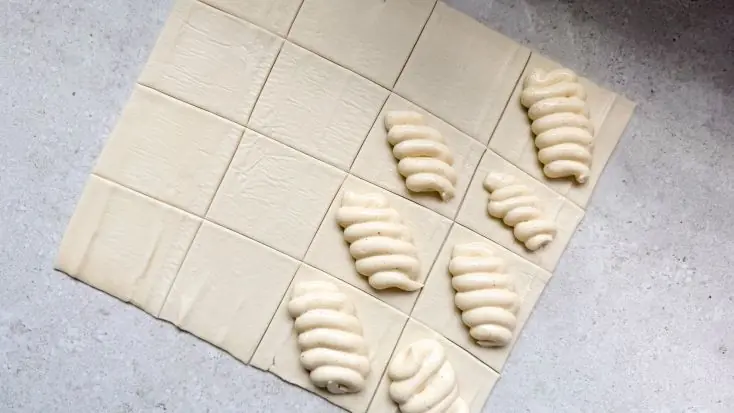 מזלפים את מלית הגבינה במרכז כל ריבוע בצק