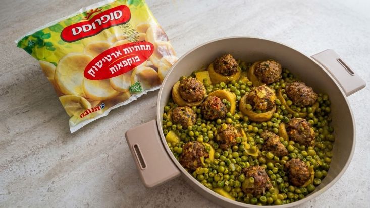 תחתיות ארטישוק ממולאות בשר עם אפונה ותפוחי אדמה בסיר שמונח על שיש, לצד אריזת תחתיות ארטישוק של סנפרוסט.